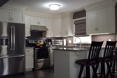 Example of a mid-sized u-shaped eat-in kitchen design in Toronto with stainless steel appliances and a peninsula