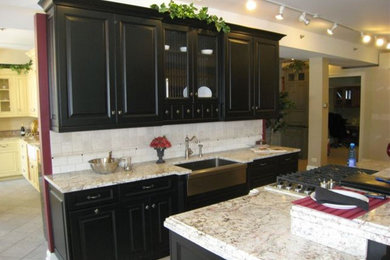 Example of a small classic galley limestone floor and gray floor eat-in kitchen design in Chicago with a farmhouse sink, raised-panel cabinets, black cabinets, stainless steel appliances, an island, granite countertops, gray backsplash and limestone backsplash