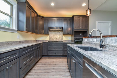Mid-sized arts and crafts u-shaped light wood floor and brown floor open concept kitchen photo in Other with an undermount sink, shaker cabinets, dark wood cabinets, quartzite countertops, beige backsplash, stone slab backsplash, stainless steel appliances, an island and beige countertops