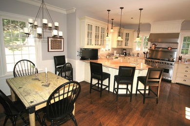 Exempel på ett lantligt kök, med en undermonterad diskho, luckor med glaspanel, beige skåp, beige stänkskydd, granitbänkskiva, rostfria vitvaror och mellanmörkt trägolv