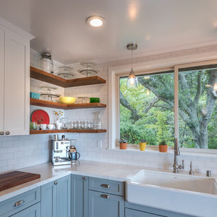 Inspiration pour une cuisine américaine rustique de taille moyenne avec un évier de ferme, un placard à porte shaker, des portes de placard blanches, une crédence blanche, une crédence en carreau de céramique, un sol en bois brun et aucun îlot.