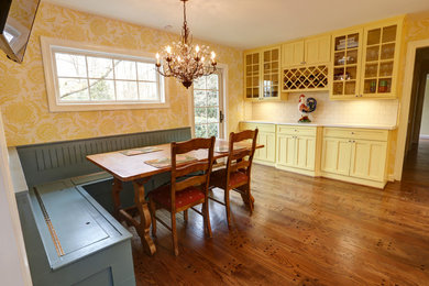 Foto på ett amerikanskt l-kök, med en rustik diskho, luckor med infälld panel, gula skåp, bänkskiva i kvartsit, vitt stänkskydd, stänkskydd i tunnelbanekakel, rostfria vitvaror och mellanmörkt trägolv
