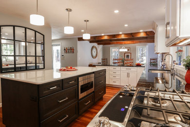 ボストンにあるトランジショナルスタイルのおしゃれなキッチン (アンダーカウンターシンク、シェーカースタイル扉のキャビネット、黒いキャビネット、クオーツストーンカウンター、白いキッチンパネル、セラミックタイルのキッチンパネル、シルバーの調理設備、無垢フローリング、オレンジの床、白いキッチンカウンター) の写真