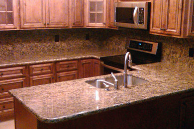 Kitchen photo in Phoenix with a double-bowl sink, beaded inset cabinets, medium tone wood cabinets, stainless steel appliances and a peninsula