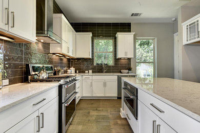Large trendy l-shaped medium tone wood floor and brown floor kitchen photo in Austin with an undermount sink, shaker cabinets, white cabinets, quartz countertops, gray backsplash, porcelain backsplash, stainless steel appliances and an island