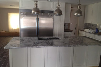 Example of a large transitional l-shaped open concept kitchen design in Tampa with a double-bowl sink, recessed-panel cabinets, white cabinets, granite countertops, gray backsplash, stainless steel appliances and an island