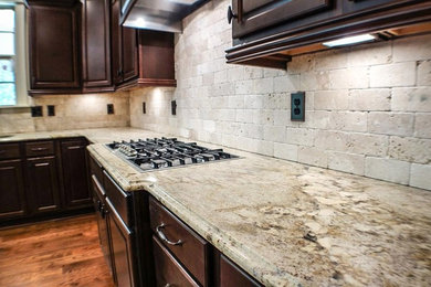 Classic kitchen in Los Angeles with a submerged sink, granite worktops, stone tiled splashback, raised-panel cabinets, dark wood cabinets, beige splashback, dark hardwood flooring and brown floors.