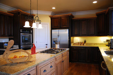 Photo of a large u-shaped enclosed kitchen in Other with a double-bowl sink, dark wood cabinets, granite worktops, yellow splashback, stainless steel appliances, medium hardwood flooring and an island.