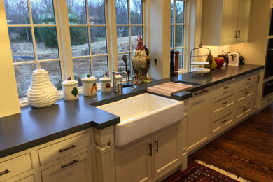 Large farmhouse l-shaped medium tone wood floor and brown floor enclosed kitchen photo in Philadelphia with a farmhouse sink, shaker cabinets, white cabinets, quartz countertops, stainless steel appliances and an island