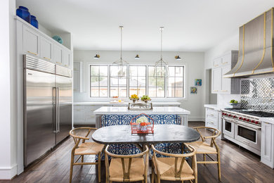 Klassische Wohnküche mit Schrankfronten im Shaker-Stil, weißen Schränken, Küchengeräten aus Edelstahl, dunklem Holzboden und Kücheninsel in Houston