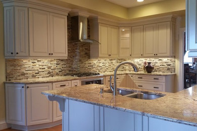 Example of a mid-sized classic l-shaped medium tone wood floor eat-in kitchen design in Richmond with an undermount sink, raised-panel cabinets, beige cabinets, granite countertops, brown backsplash, glass tile backsplash, stainless steel appliances and a peninsula