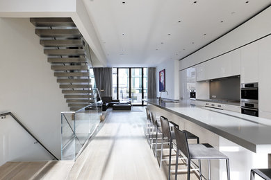 Example of a trendy open concept kitchen design in New York with a double-bowl sink, flat-panel cabinets, white cabinets and gray backsplash