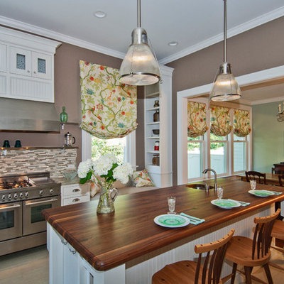 Inspiration for a timeless eat-in kitchen remodel in Other with matchstick tile backsplash, wood countertops, multicolored backsplash, stainless steel appliances, white cabinets and recessed-panel cabinets