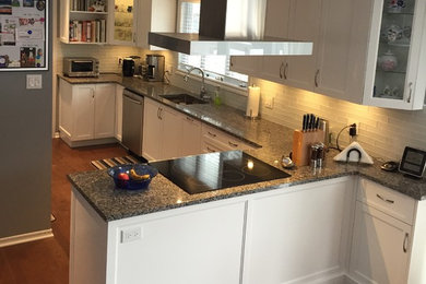Photo of a medium sized traditional single-wall kitchen/diner in Montreal with a submerged sink, recessed-panel cabinets, white cabinets, engineered stone countertops, white splashback, glass tiled splashback, white appliances, dark hardwood flooring, a breakfast bar and brown floors.