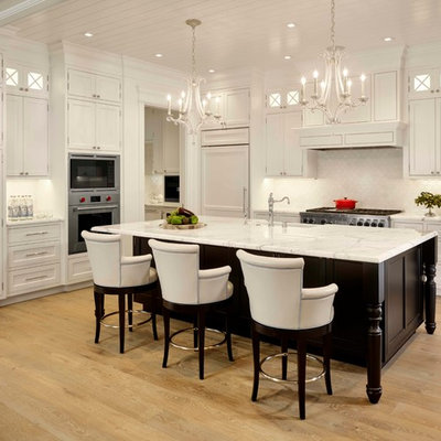 Example of a large classic l-shaped light wood floor open concept kitchen design in San Francisco with white cabinets, marble countertops, white backsplash, an island, shaker cabinets, paneled appliances, a farmhouse sink and ceramic backsplash