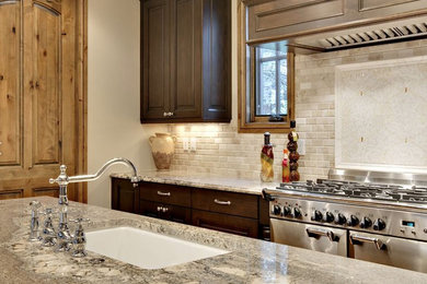Enclosed kitchen - large transitional u-shaped enclosed kitchen idea in New York with an undermount sink, raised-panel cabinets, dark wood cabinets, multicolored backsplash, stone tile backsplash, stainless steel appliances, an island and granite countertops