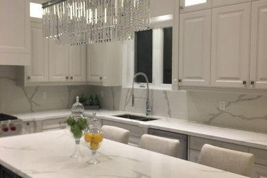 Inspiration for a large modern u-shaped marble floor and white floor eat-in kitchen remodel in Toronto with an undermount sink, raised-panel cabinets, white cabinets, quartzite countertops, white backsplash, marble backsplash, stainless steel appliances, an island and white countertops