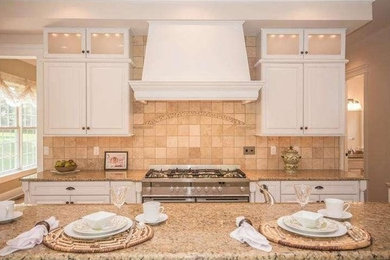 Inspiration for a large transitional l-shaped medium tone wood floor and brown floor open concept kitchen remodel in Philadelphia with an undermount sink, raised-panel cabinets, white cabinets, granite countertops, white backsplash, ceramic backsplash, paneled appliances and an island