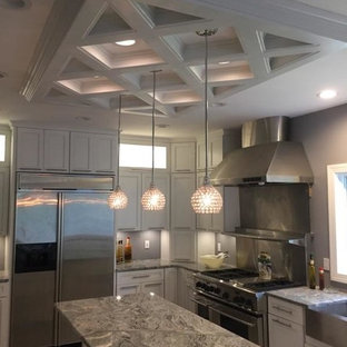 Design ideas for a large shabby-chic style u-shaped eat-in kitchen in Philadelphia with a farmhouse sink, glass-front cabinets, white cabinets, granite benchtops, porcelain splashback, stainless steel appliances, porcelain floors and a peninsula.