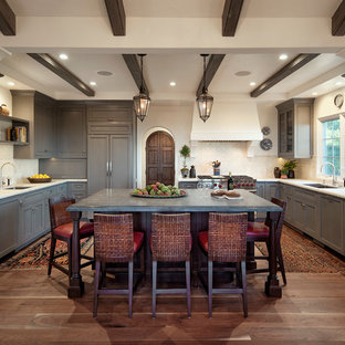 Example of a large tuscan u-shaped medium tone wood floor and brown floor kitchen design in Santa Barbara with gray cabinets, marble countertops, white backsplash, ceramic backsplash, paneled appliances, an island, a double-bowl sink and shaker cabinets