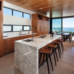 Open concept kitchen - mid-sized coastal concrete floor and gray floor open concept kitchen idea in Los Angeles with an undermount sink, flat-panel cabinets, medium tone wood cabinets, marble countertops, paneled appliances and an island