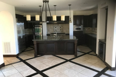 Example of a mid-sized transitional u-shaped dark wood floor and brown floor open concept kitchen design in Orange County with an undermount sink, white backsplash, paneled appliances, an island, black countertops, recessed-panel cabinets, dark wood cabinets, granite countertops and stone tile backsplash