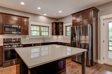 Mid-sized elegant u-shaped dark wood floor and brown floor enclosed kitchen photo in Other with an undermount sink, beaded inset cabinets, dark wood cabinets, quartz countertops, white backsplash, porcelain backsplash, stainless steel appliances and an island