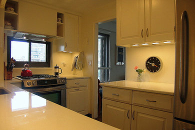 ニューヨークにあるお手頃価格の中くらいなコンテンポラリースタイルのおしゃれなキッチン (アンダーカウンターシンク、レイズドパネル扉のキャビネット、白いキャビネット、クオーツストーンカウンター、白いキッチンパネル、シルバーの調理設備、セラミックタイルの床、セラミックタイルのキッチンパネル、茶色い床、白いキッチンカウンター、アイランドなし) の写真