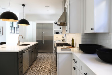 Photo of a large modern l-shaped kitchen pantry in Los Angeles with a submerged sink, shaker cabinets, white cabinets, quartz worktops, white splashback, metro tiled splashback, stainless steel appliances, ceramic flooring, an island, multi-coloured floors and white worktops.