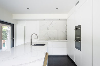 Esempio di un cucina con isola centrale contemporaneo con paraspruzzi bianco, paraspruzzi con piastrelle in ceramica, pavimento con piastrelle in ceramica, pavimento nero e top bianco