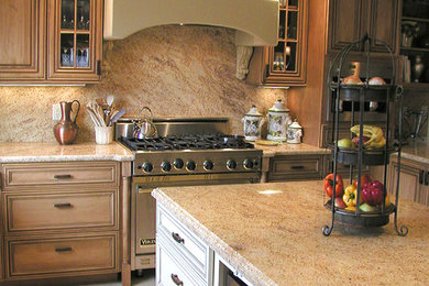 Foto de cocina tradicional grande con puertas de armario de madera oscura, encimera de granito, salpicadero beige, salpicadero de losas de piedra y electrodomésticos de acero inoxidable
