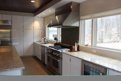 Photo of a medium sized contemporary galley kitchen in New York with a submerged sink, flat-panel cabinets, white cabinets, granite worktops, window splashback, stainless steel appliances, an island and brown floors.