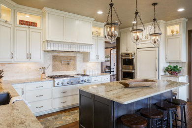 Example of a classic u-shaped dark wood floor and brown floor kitchen design in Other with an undermount sink, recessed-panel cabinets, white cabinets, beige backsplash, paneled appliances, an island and beige countertops