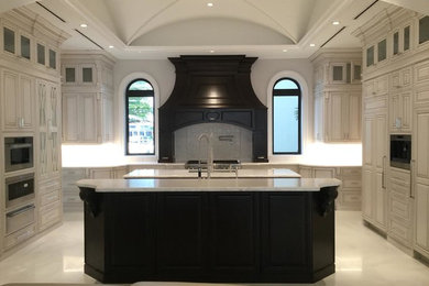 Large traditional u-shaped kitchen/diner in Miami with a submerged sink, raised-panel cabinets, white cabinets, marble worktops, white splashback, ceramic splashback, integrated appliances, marble flooring, multiple islands and white floors.