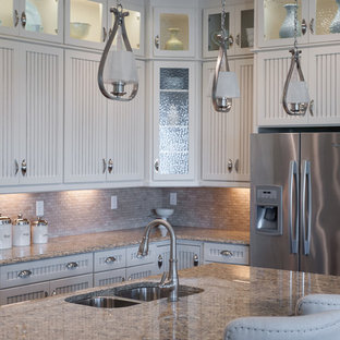 Photo of a mid-sized country single-wall eat-in kitchen in Jacksonville with a double-bowl sink, louvered cabinets, white cabinets, marble benchtops, beige splashback, stone tile splashback, stainless steel appliances, vinyl floors and with island.