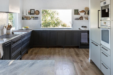 Example of a large galley light wood floor eat-in kitchen design in San Francisco with an undermount sink, beaded inset cabinets, black cabinets, marble countertops, white backsplash, marble backsplash, paneled appliances, no island and gray countertops