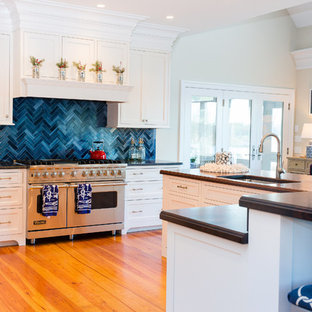Inspiration for a beach style eat-in kitchen in Baltimore with limestone benchtops, blue splashback, stainless steel appliances, light hardwood floors and a peninsula.