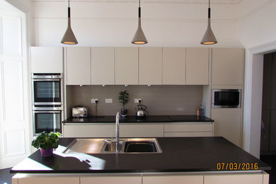 Bild på ett mellanstort funkis linjärt kök och matrum, med en undermonterad diskho, släta luckor, beige skåp, bänkskiva i koppar, grått stänkskydd, stänkskydd i porslinskakel, rostfria vitvaror, vinylgolv och en köksö