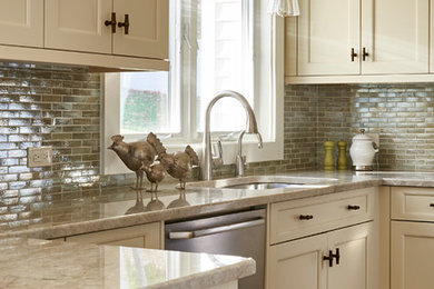 Example of a mid-sized transitional u-shaped medium tone wood floor and brown floor enclosed kitchen design in New York with an undermount sink, recessed-panel cabinets, beige cabinets, granite countertops, metallic backsplash, stone tile backsplash, stainless steel appliances, a peninsula and beige countertops