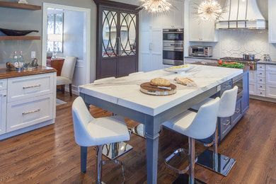 Example of a mid-sized transitional l-shaped medium tone wood floor and brown floor eat-in kitchen design in Boston with an undermount sink, recessed-panel cabinets, white cabinets, marble countertops, yellow backsplash, ceramic backsplash, stainless steel appliances and two islands
