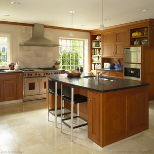 Photo of an eclectic kitchen in Detroit with stainless steel appliances, an undermount sink, shaker cabinets, medium wood cabinets, soapstone benchtops, beige splashback and stone tile splashback.