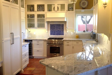 Ejemplo de cocina clásica de tamaño medio con despensa, fregadero bajoencimera, armarios con rebordes decorativos, puertas de armario blancas, encimera de granito, salpicadero beige, salpicadero de azulejos de porcelana, electrodomésticos con paneles, suelo de baldosas de terracota, península y suelo marrón