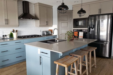 Mid-sized transitional vinyl floor eat-in kitchen photo in Edmonton with a double-bowl sink, shaker cabinets, blue cabinets, quartzite countertops, white backsplash, subway tile backsplash, black appliances, an island and gray countertops