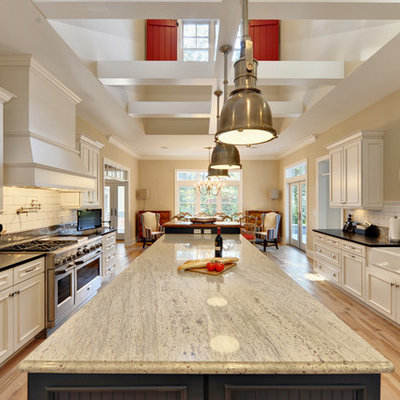Beach style eat-in kitchen photo in Philadelphia with stainless steel appliances, subway tile backsplash, a farmhouse sink, granite countertops, recessed-panel cabinets, white cabinets, white backsplash and black countertops