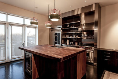 Exempel på ett mellanstort modernt linjärt kök och matrum, med träbänkskiva, rostfria vitvaror, mörkt trägolv, en köksö, släta luckor, skåp i rostfritt stål, en undermonterad diskho, grått stänkskydd, stänkskydd i glaskakel och brunt golv