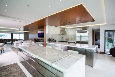 Inspiration for a large modern u-shaped kitchen/diner in Vancouver with a submerged sink, flat-panel cabinets, stainless steel cabinets, quartz worktops, white splashback, stone slab splashback, stainless steel appliances and limestone flooring.