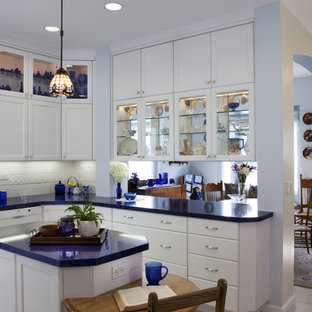 This is an example of a mid-sized eclectic u-shaped separate kitchen in San Diego with glass-front cabinets, an undermount sink, white cabinets, solid surface benchtops, white splashback, porcelain splashback, panelled appliances, ceramic floors, with island, white floor and blue benchtop.