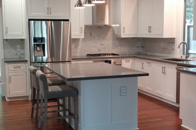Inspiration for a mid-sized contemporary l-shaped medium tone wood floor eat-in kitchen remodel in Houston with an undermount sink, shaker cabinets, white cabinets, quartz countertops, gray backsplash, mosaic tile backsplash, stainless steel appliances and an island