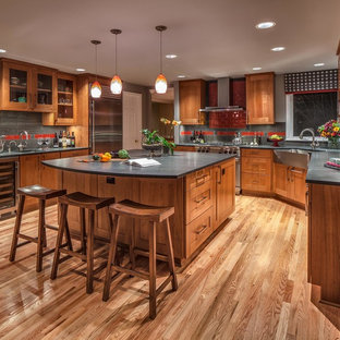 Modelo de cocina en U, tradicional, grande, cerrada, con fregadero sobremueble, encimera de esteatita, armarios estilo shaker, puertas de armario de madera oscura, salpicadero rojo, salpicadero de azulejos de cerámica, electrodomésticos de acero inoxidable, una isla, suelo de madera en tonos medios y suelo marrón