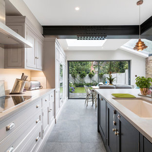 Immagine di una cucina contemporanea di medie dimensioni con lavello integrato, ante in stile shaker, ante grigie, top in cemento, paraspruzzi bianco, elettrodomestici in acciaio inossidabile, pavimento in cemento, isola e pavimento grigio